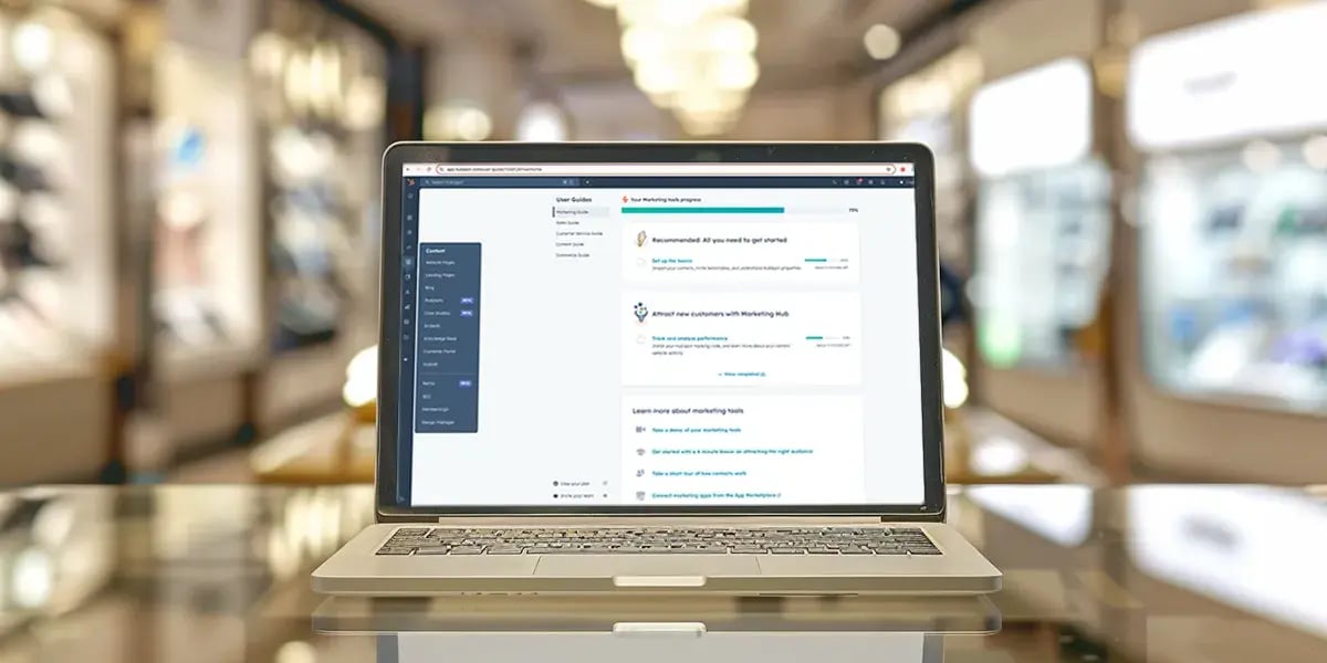 silver laptop on glass table with hubspot content hub dashboard on screen