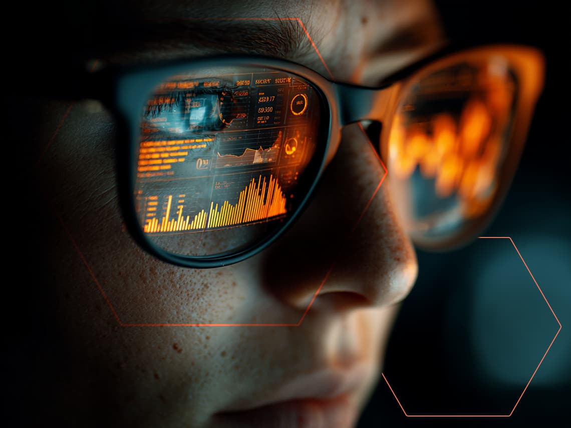 close up of a person wearing glasses. in the reflection of their glasses we see charts and other data streams.